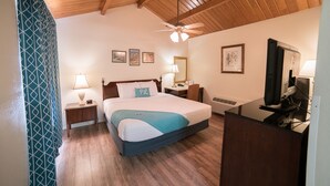 Un dormitorio con cama, mesitas de noche, un escritorio con computadora y un ventilador de techo.