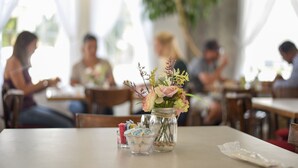 Una mesa de comedor con un tarro de flores y un pequeño recipiente con cubiertos.