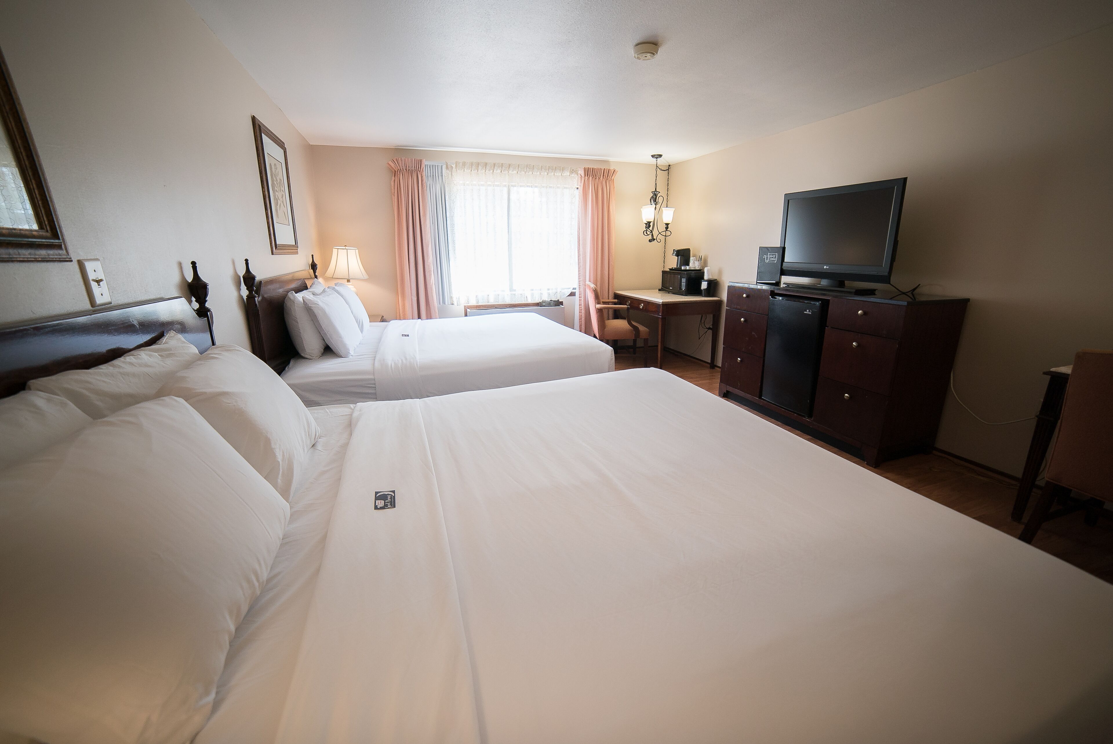 A hotel room with two beds, a desk, a television, and a wardrobe.