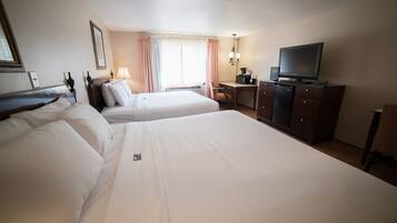 A hotel room with two beds, a desk, a television, and a wardrobe.