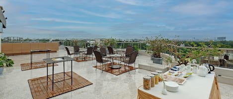 A rooftop terrace with outdoor seating, a chess table, and a buffet setup.