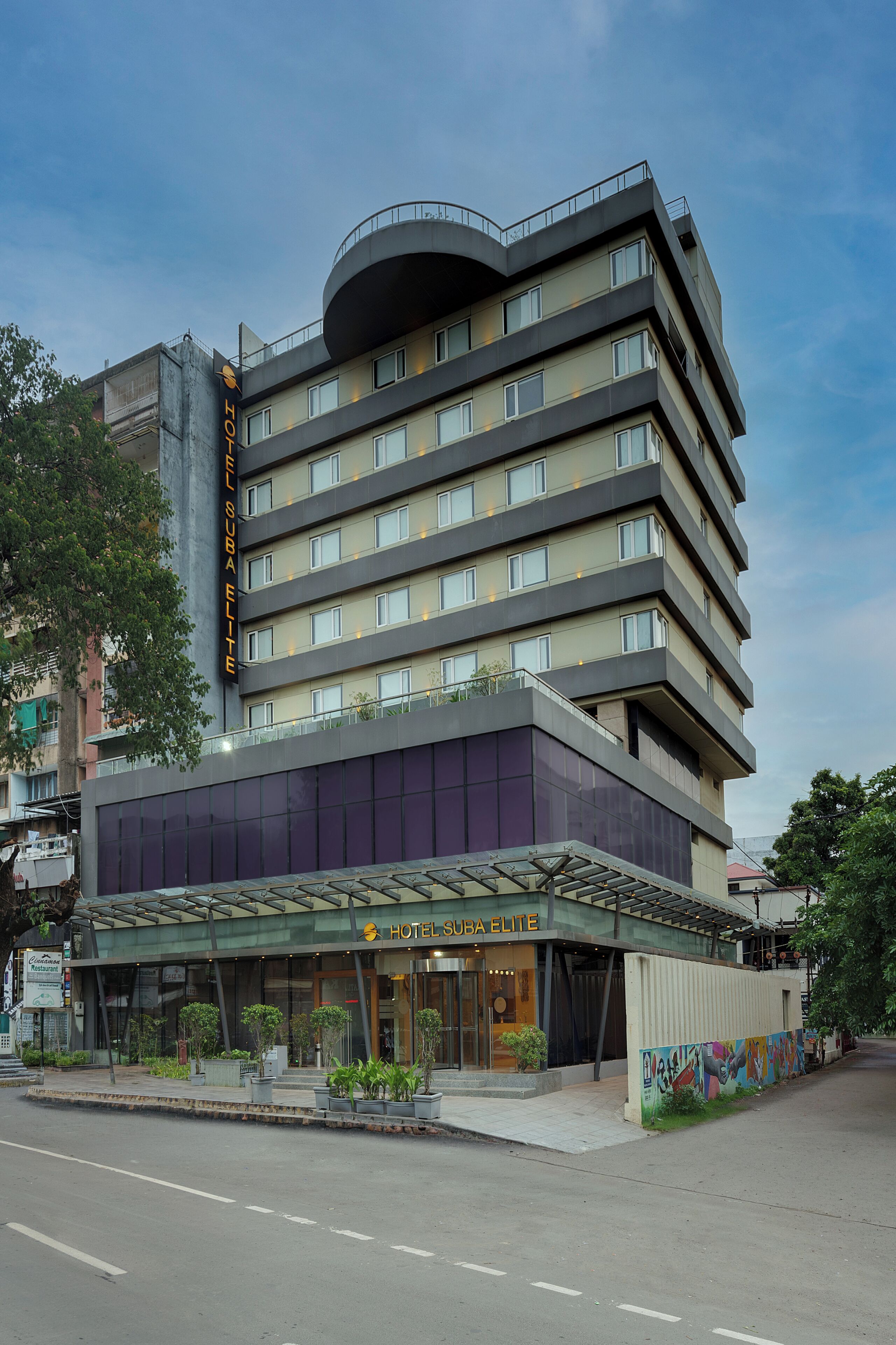 A multi-story hotel with a modern design, featuring a prominent entrance with a glass facade and a rooftop terrace.