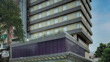 A multi-story hotel with a modern design, featuring a prominent entrance with a glass facade and a rooftop terrace.