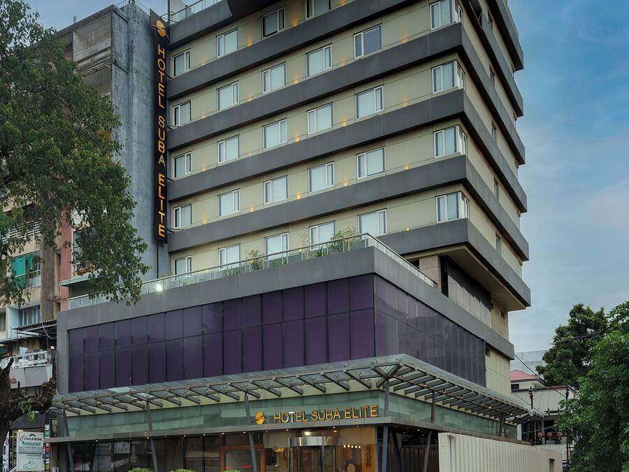 A multi-story hotel with a modern design, featuring a prominent entrance with a glass facade and a rooftop terrace.
