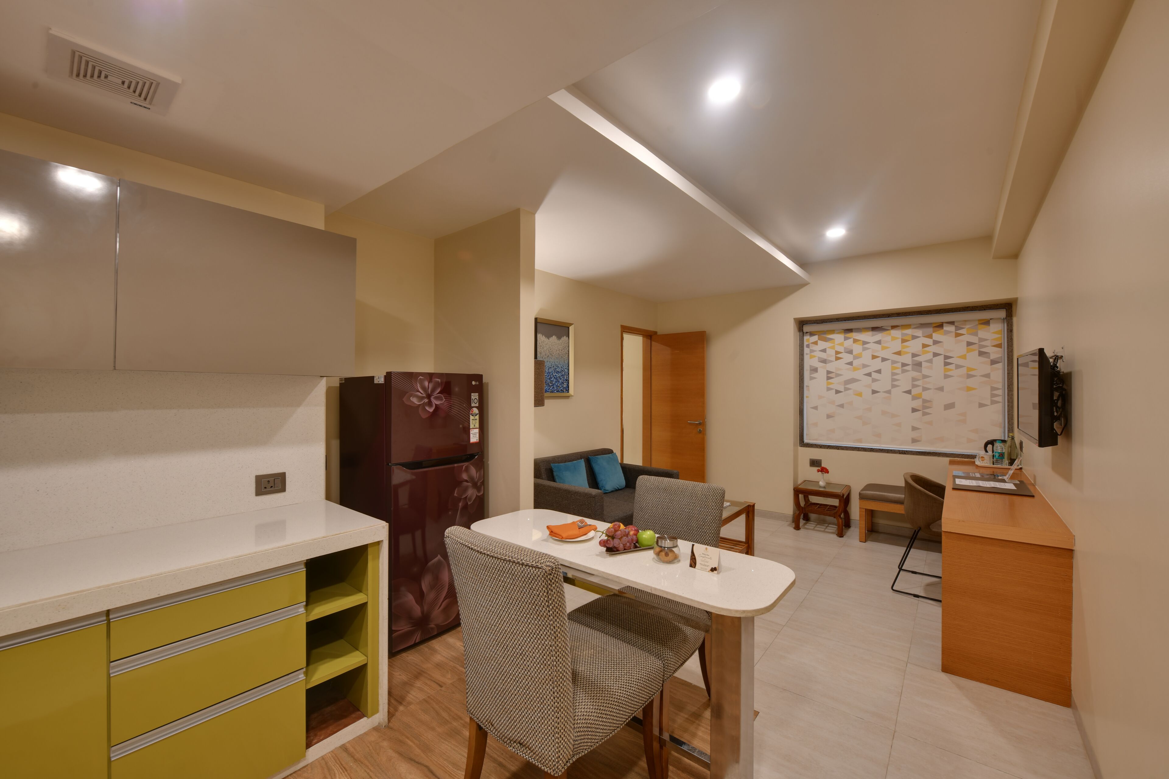 A compact kitchen with a refrigerator, a dining table, and a sofa in the adjacent living area.