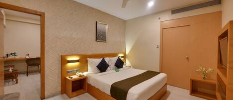A hotel room with a bed, bedside table, chair, desk, and wardrobe.