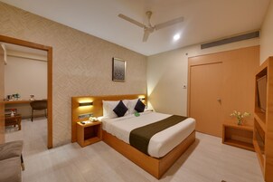 Una habitación de hotel con cama, mesita de noche, silla, escritorio y armario.