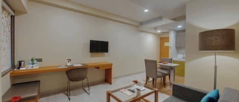 A modern living room with a sofa, coffee table, and a desk area with a flat-screen TV.