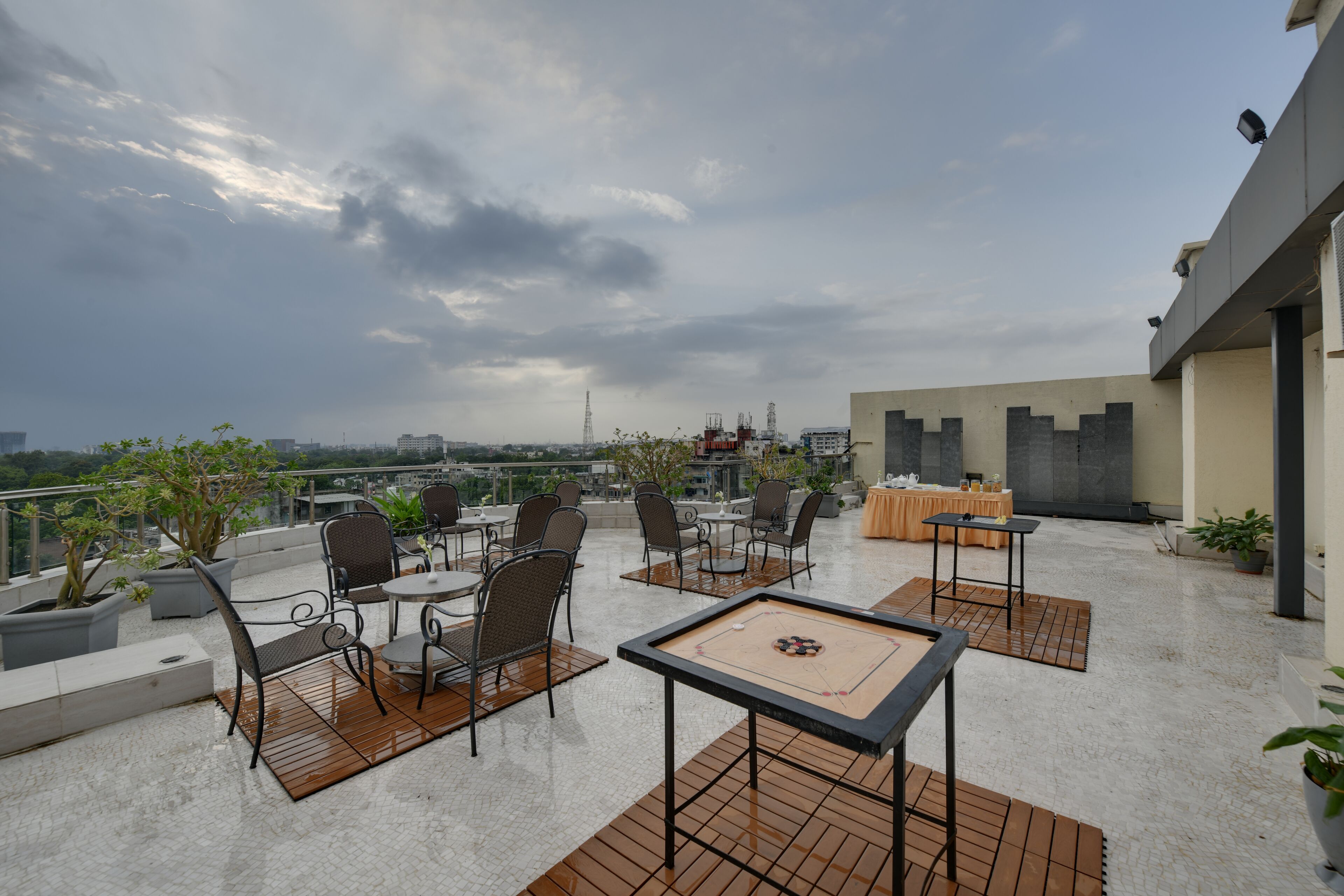 En tagterrasse med udendørs siddepladser, et bord med et brætspil og udsigt over byens skyline.