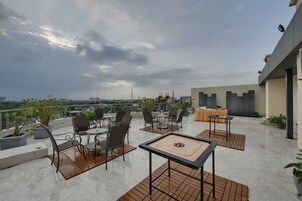 Terraza en la azotea con mobiliario exterior, una mesa con un juego de mesa y vistas del horizonte de la ciudad.