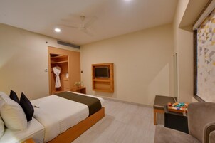 Habitación de hotel con cama, televisión, armario y zona de estar.