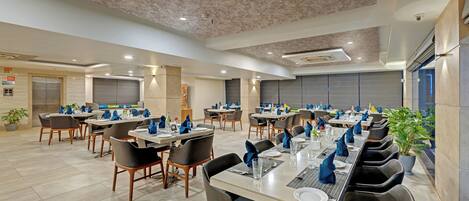 A spacious dining area with multiple tables and chairs, equipped with modern amenities.