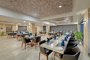 A spacious dining area with multiple tables and chairs, equipped with modern amenities.