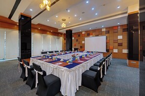 A conference room with a long table, chairs, and a projector screen. - Hotel Suba Elite Vadodara (Vadodara)