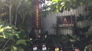 A sign for Chada Thai Hotel with a traditional Thai architectural style, surrounded by lush greenery and potted plants. - Chada Thai House (Pattaya)