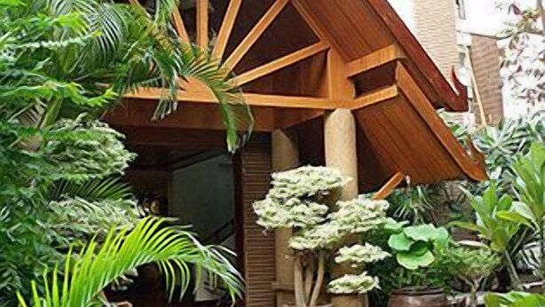 A wooden structure with a sloped roof, surrounded by various potted plants. - Chada Thai House (Pattaya)