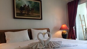 A hotel room with a neatly made bed, a painting on the wall, a lamp, and a window with curtains. - Chada Thai House (Pattaya)