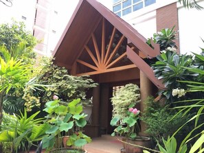 A building with a wooden structure and a garden with various plants. - Chada Thai House (Pattaya)