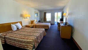 Une chambre d’hôtel avec deux lits, un bureau, une chaise et un téléviseur.