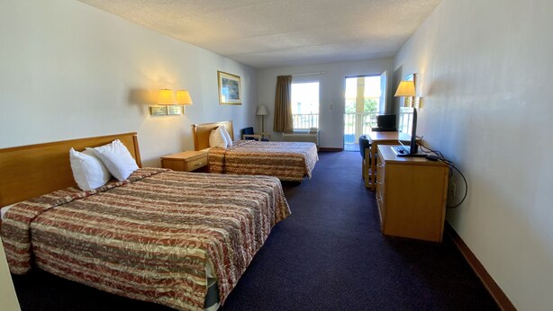 Une chambre d’hôtel avec deux lits, un bureau, une chaise et un téléviseur.