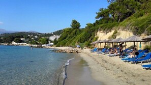 Perto da praia, areia branca, espreguiçadeiras, guarda-sóis 