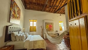 A bedroom with a bed, a hammock, a wooden door, and a window. - Casa de Los Santos Reyes Hotel Boutique Valledupar (Valledupar)