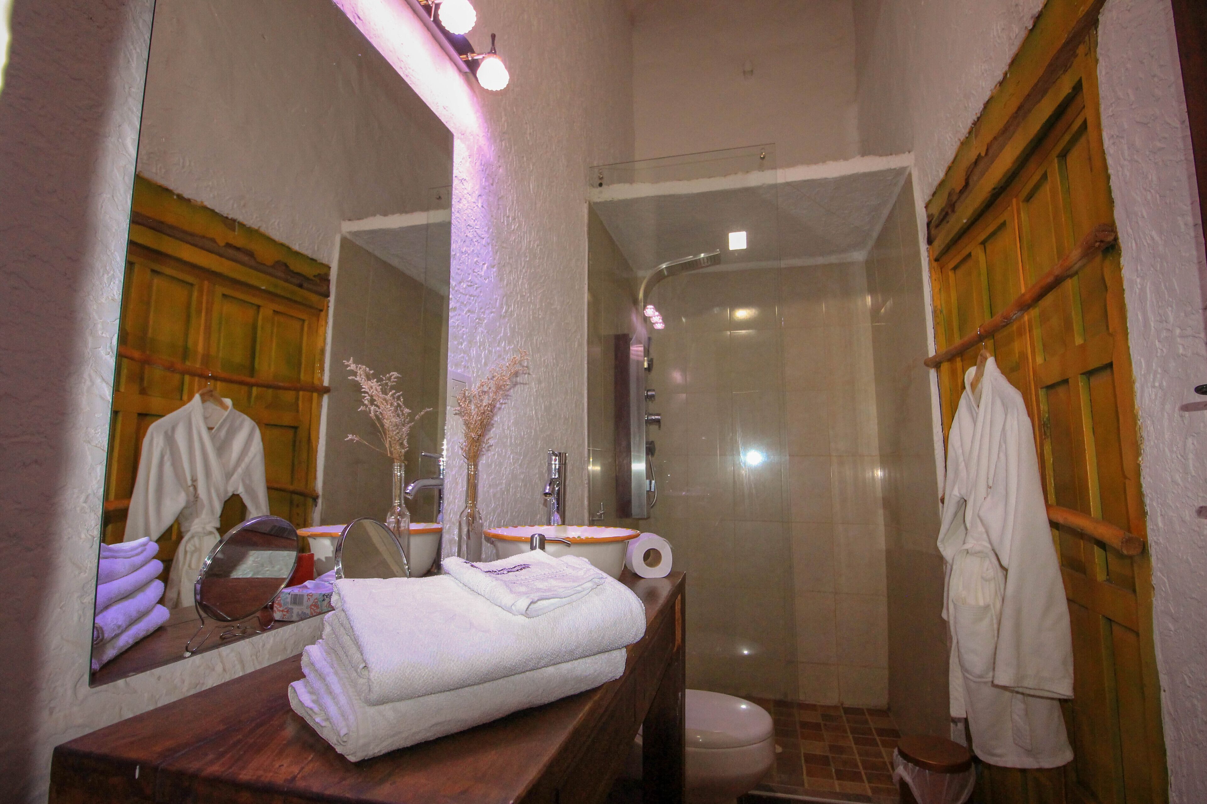 Een badkamer met een houten wastafelmeubel, een spiegel, een handdoekhouder en een douche.