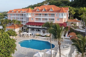 A large hotel with multiple balconies, a swimming pool, and palm trees. - Bahia Principe Escape Samaná - Hyatt Inclusive Collection - Adults Only (Samaná)