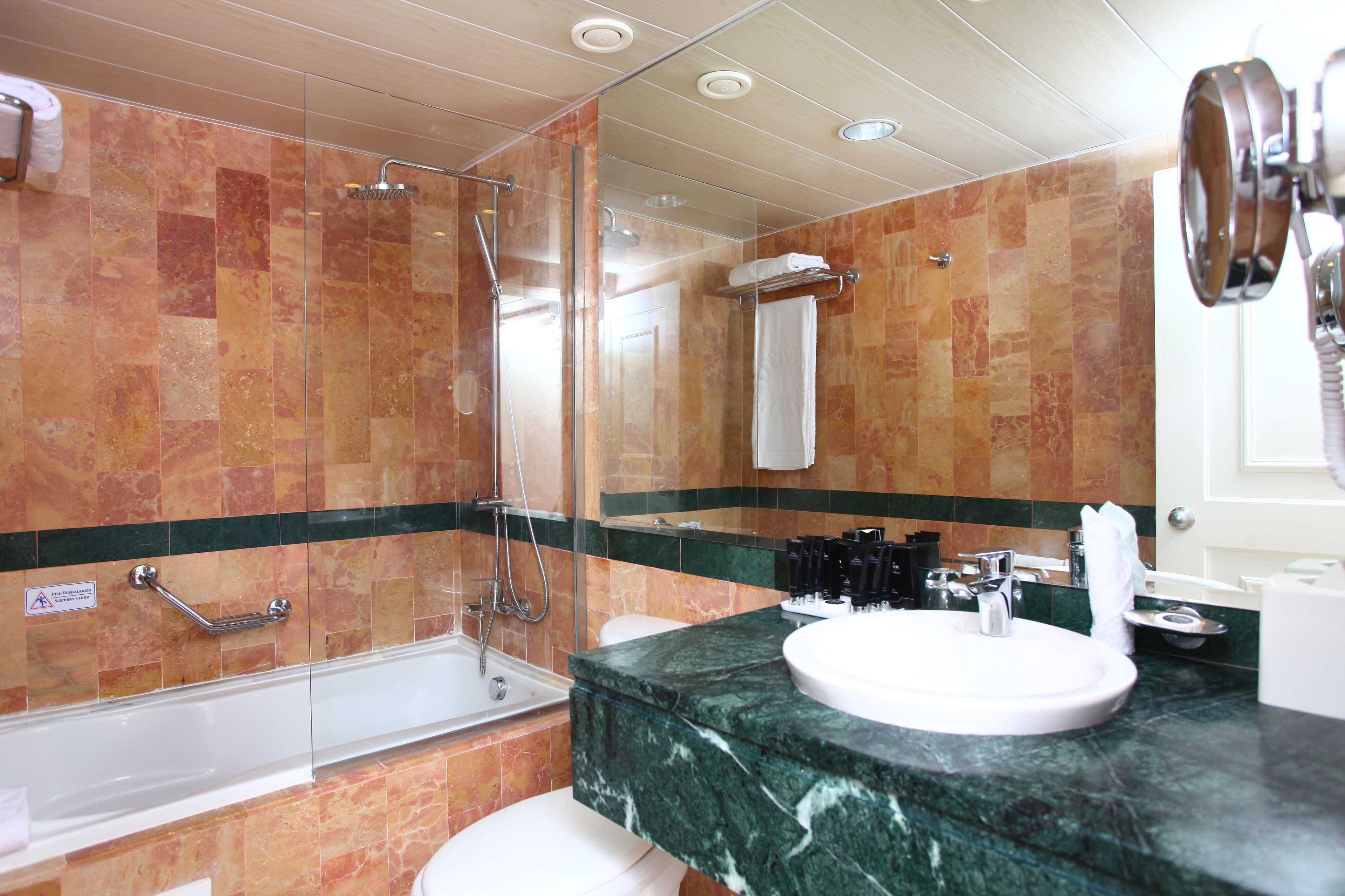 Ein Badezimmer mit einer gläsernen Duschkabine, einer weißen Badewanne und einem мраморном Waschbecken.