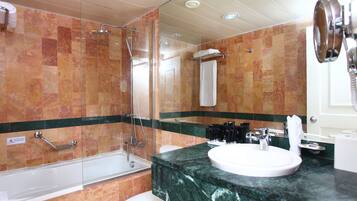 Ein Badezimmer mit einer gläsernen Duschkabine, einer weißen Badewanne und einem мраморном Waschbecken.