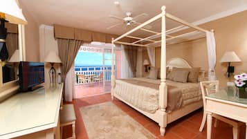 Una cama con dosel, vistas al balcón, televisión y un escritorio con lámpara.