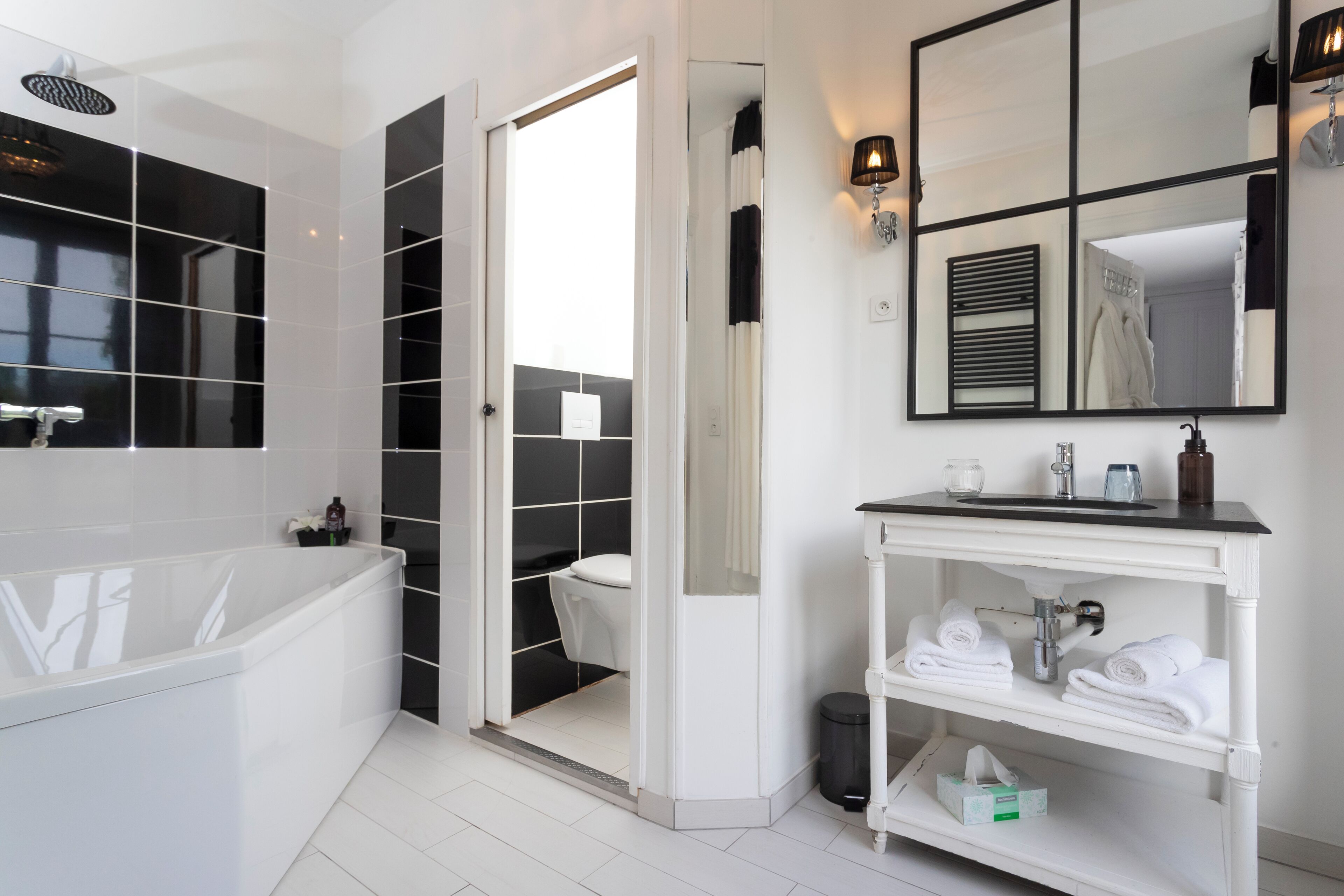 A modern bathroom with a white bathtub, a toilet, and a sink with a mirror above.