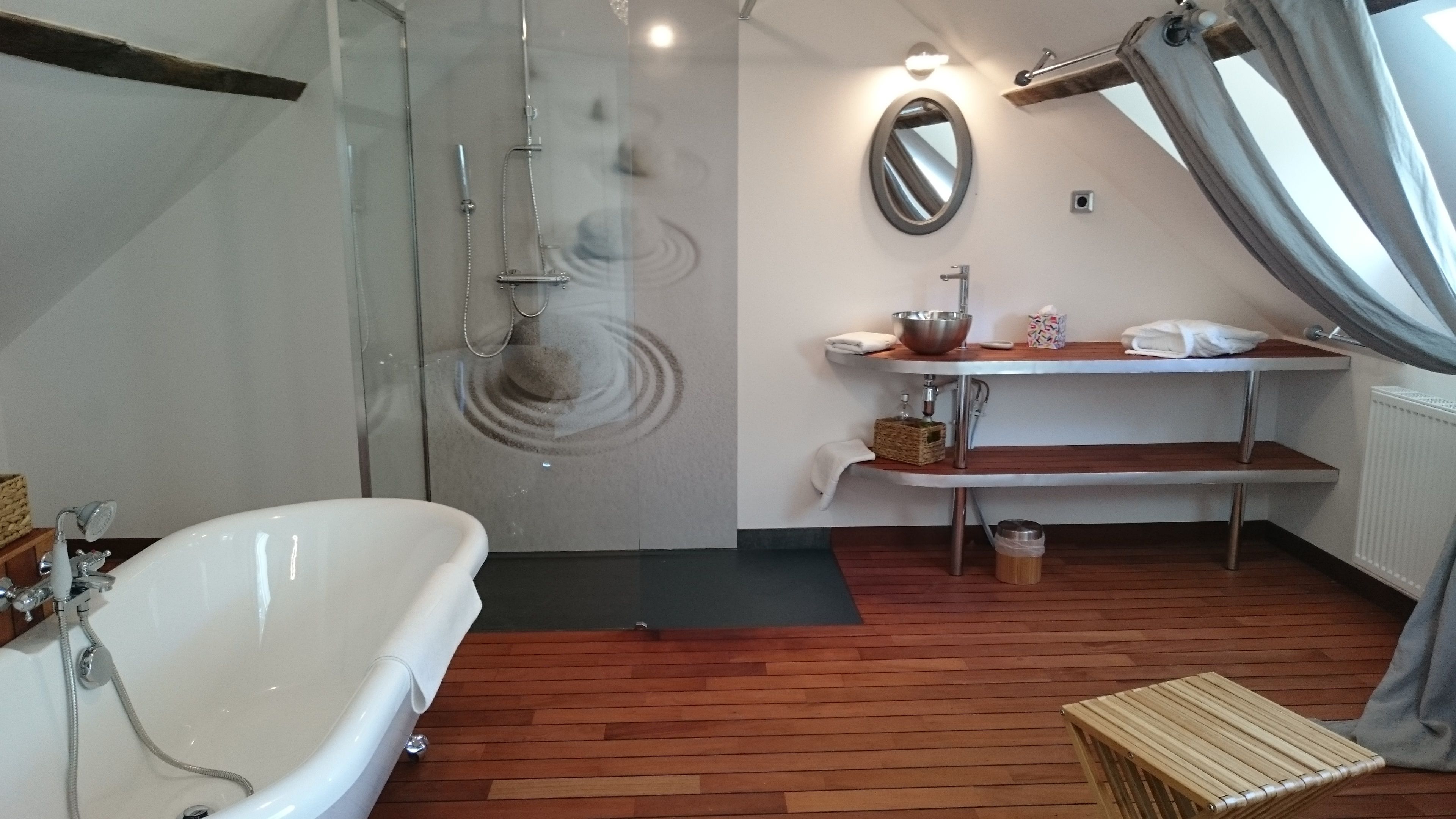 A bathroom with a bathtub, shower, and vanity with a mirror.