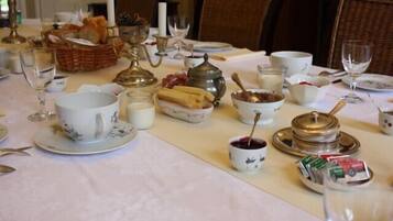 A dining table set with various dishes, including bread, cheese, and a teapot, suggesting a meal setting.