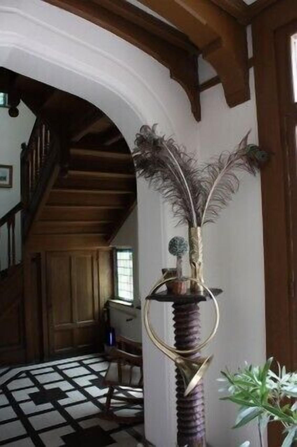 A room with a wooden staircase, a patterned floor, and a decorative plant with a hookah.