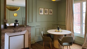 Een eetgedeelte met een ronde tafel, twee stoelen, een spiegel en foto's in lijsten aan de muur.