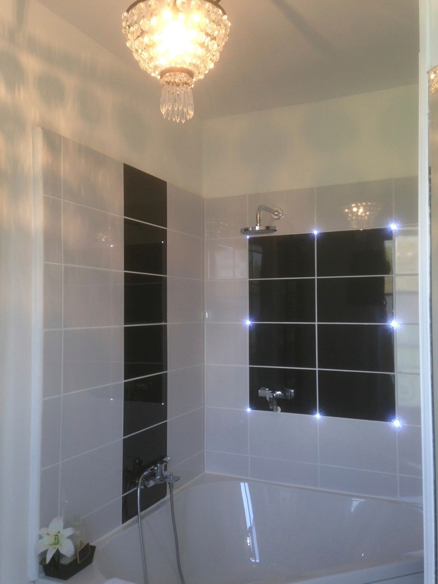 Ein modernes Badezimmer mit freistehender Badewanne, einer Handbrause und einem am Wand befestigten Wasserhahn.