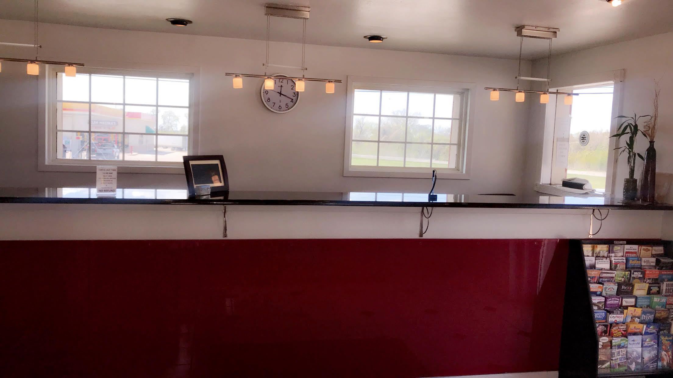 A reception desk with a clock, two windows, and hanging lights.
