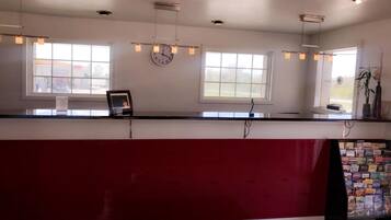 A reception desk with a clock, two windows, and hanging lights.