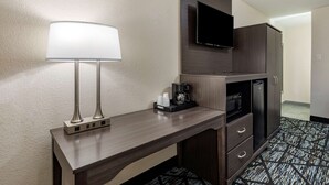 A hotel room with a wooden desk, a lamp, a television, a coffee maker, and a refrigerator. - Quality Inn Cameron (Cameron)