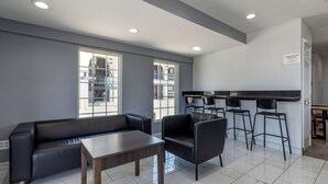 A modern lounge area with a sofa, chairs, a table, and a bar with stools. - Quality Inn Cameron (Cameron)