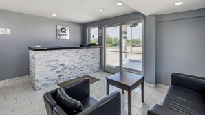 A reception area with a stone counter, leather seating, and a view through large windows. - Quality Inn Cameron (Cameron)