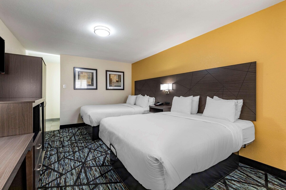 Habitación de hotel con dos camas, un escritorio y un armario.