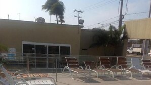 A poolside area with sun loungers and a building in the background. - Hotel Rio Inn (Boca del Río)