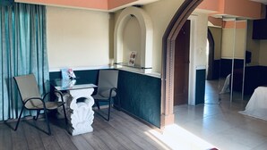 A hotel room with a wooden floor, a dining area with a table and chairs, a decorative white sculpture, and a view through an archway to another room. - Hotel Rio Inn (Boca del Río)