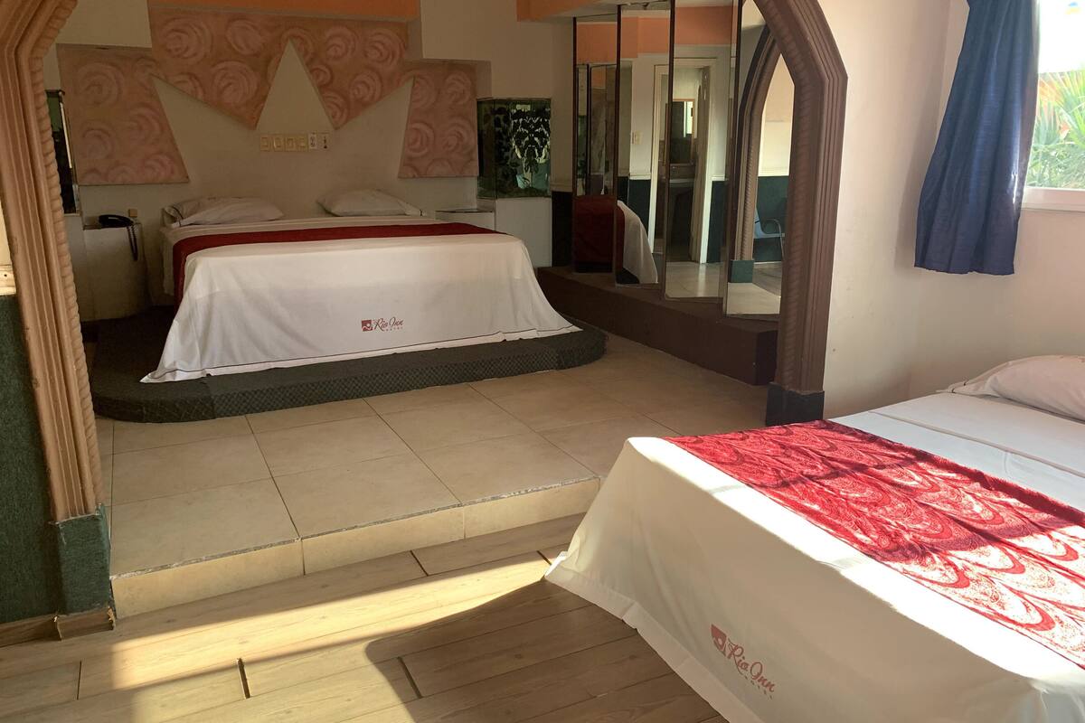 A hotel room with a bed, a mirror, and a window.