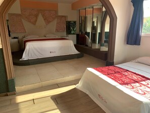 A hotel room with a bed, a mirror, and a window.