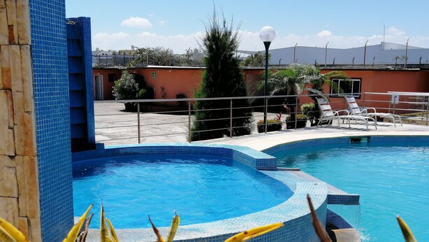 A swimming pool with a tiled edge, surrounded by lounge chairs and plants. - Hotel Rio Inn (Boca del Río)