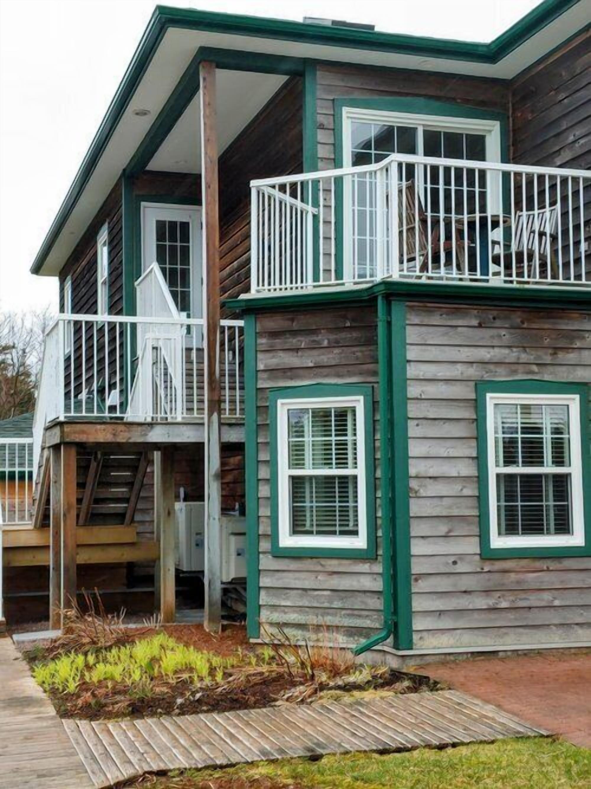 A two-story wooden house with a balcony and a covered porch.