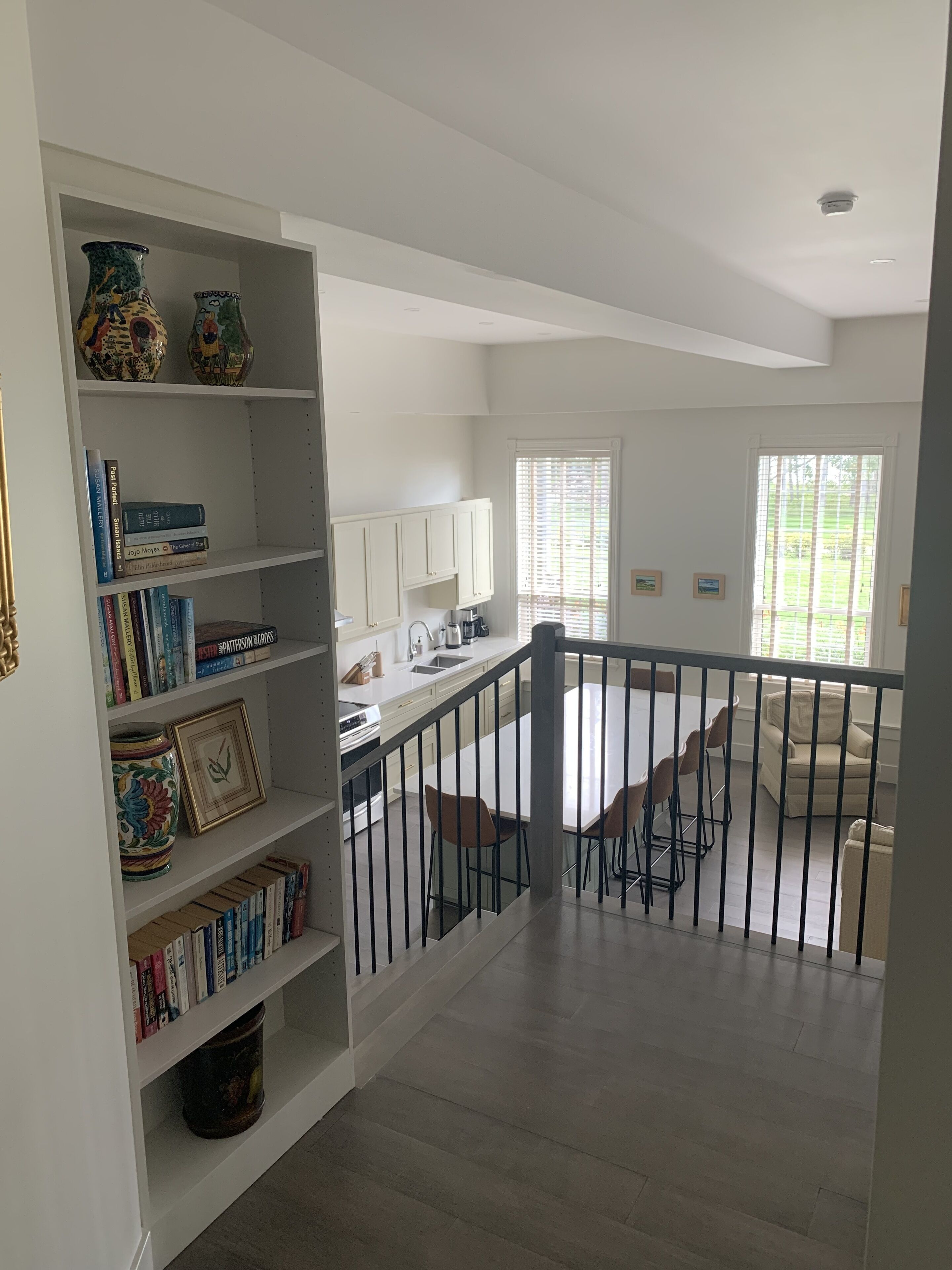 A spacious living area with a high ceiling, a staircase leading to an upper floor, and a view of a balcony.